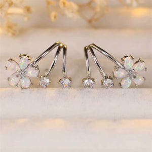 A set of silver opal crawler earrings designed as flowers with accompanying buds, displayed against a beige background from Frenelle jewellery