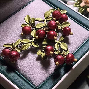 green red brooch on box