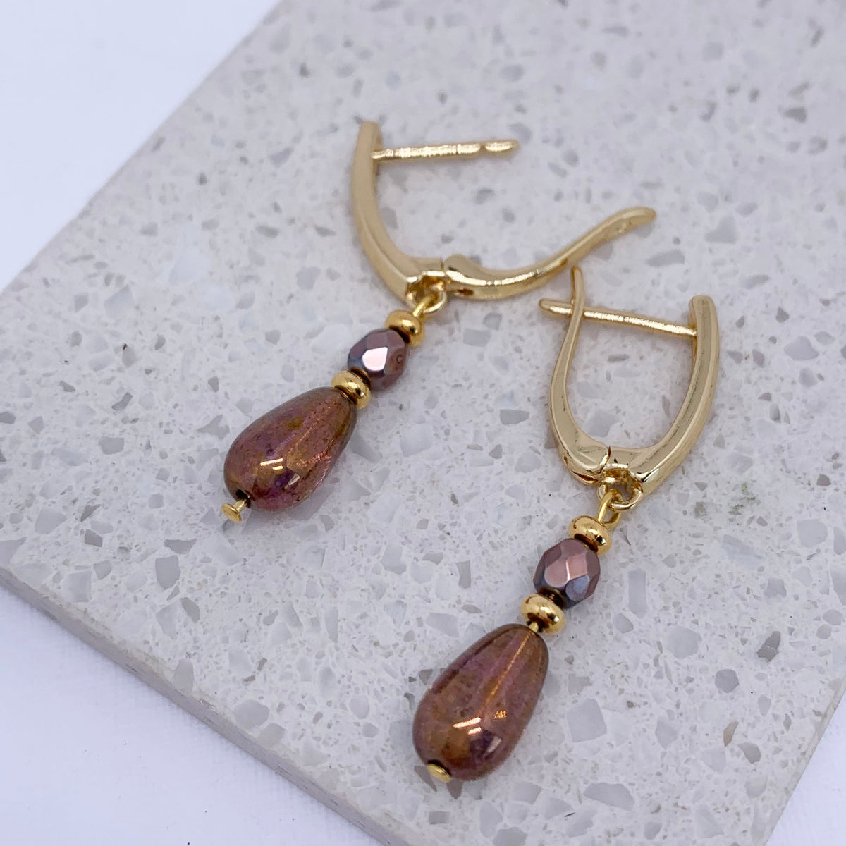 gold huggie earrings jewellery on stone