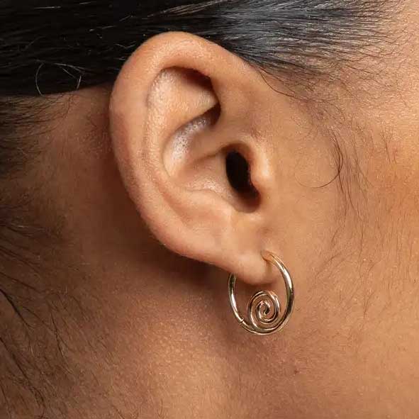 A pair of 18K gold plated huggie style earrings with a spiral design, made from 925 Sterling Silver. in ear