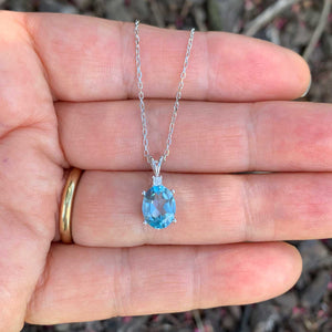 sky blue topaz necklace against hand